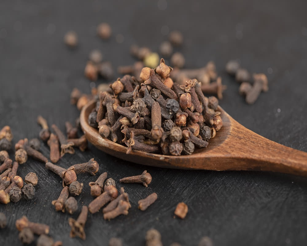 pile-dried-natural-cloves-with-wooden-spoon-black-surface1000800 丁香精油功效百科