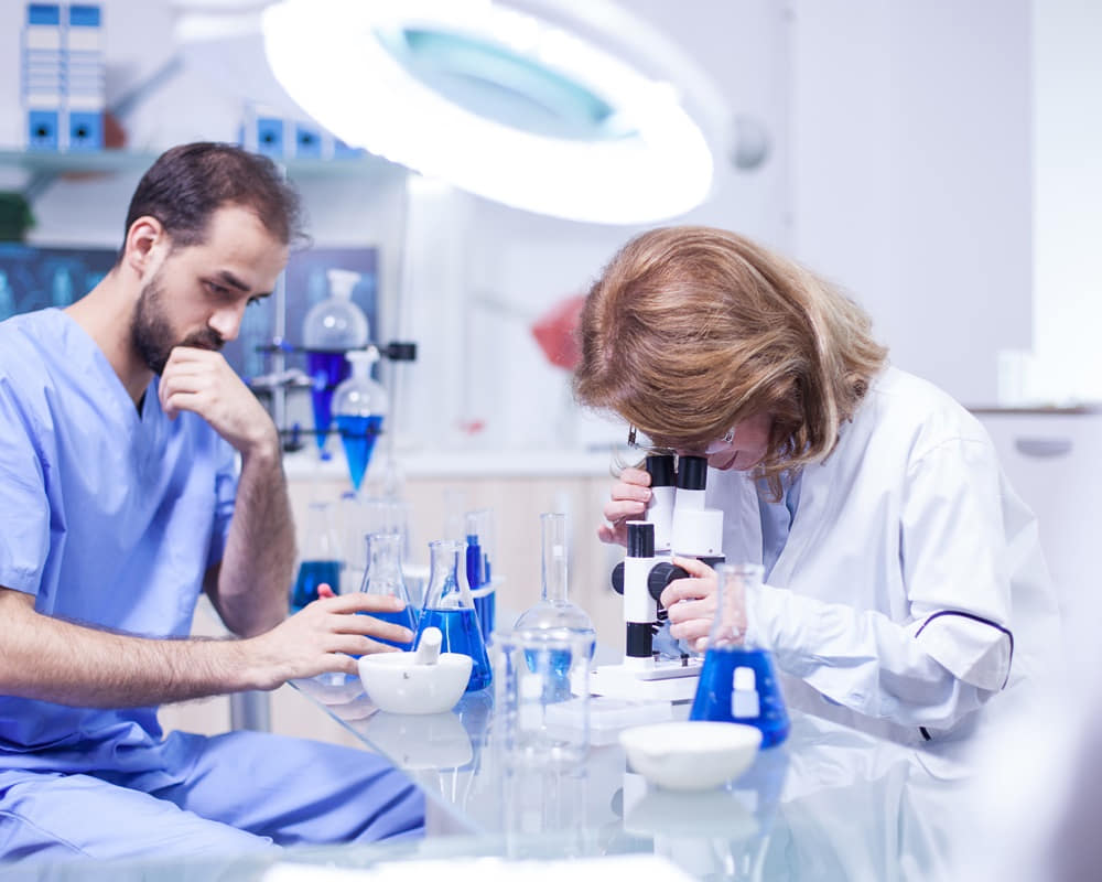 middle-age-female-scientist-working-with-microscope-laboratory-young-caucasian-male-working-as-technician-research-laboratory_medical_1000800 酸鹼體質的世紀大騙局是怎麼破滅的？